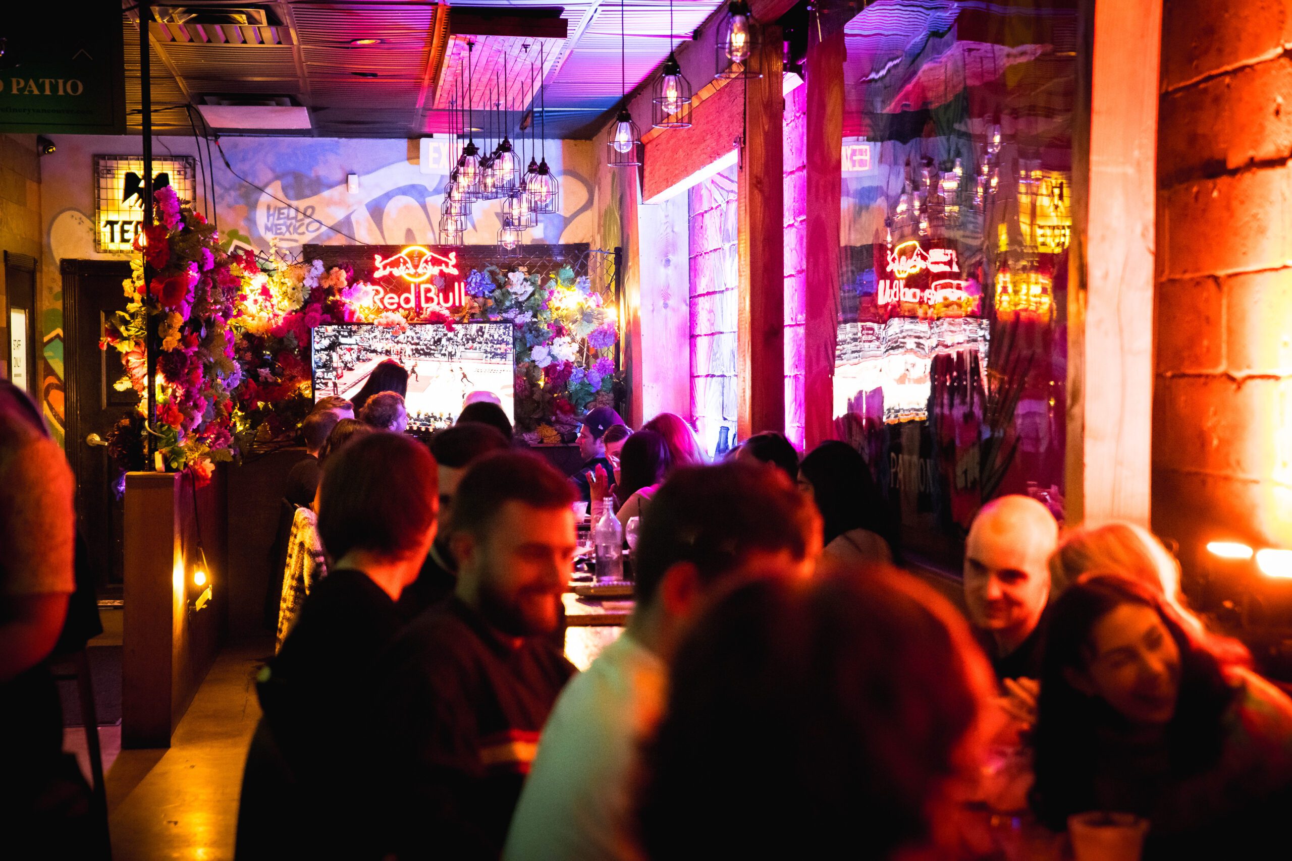 A candid shot of a busy and vibrant night at Pawn Shop YVR, with groups of people enjoying the lively atmosphere and the best tacos on Granville Street.