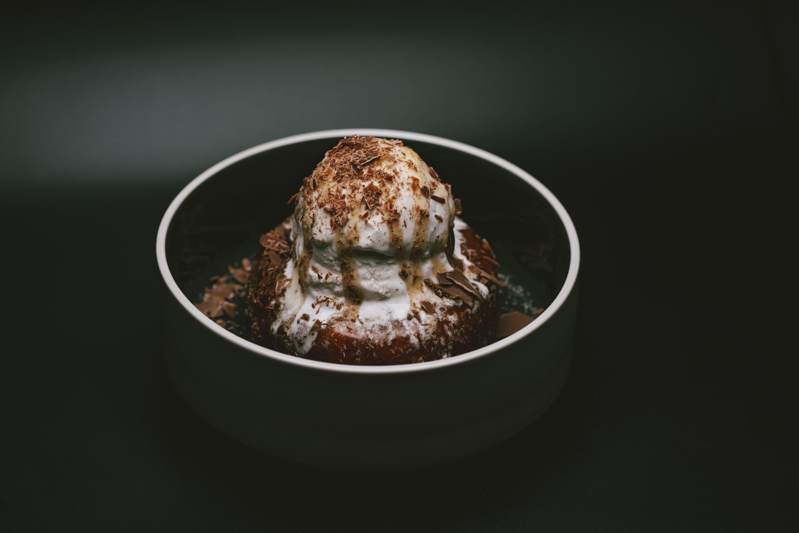 Churro donut topped with cinnamon sugar and a scoop of melting vanilla ice cream.